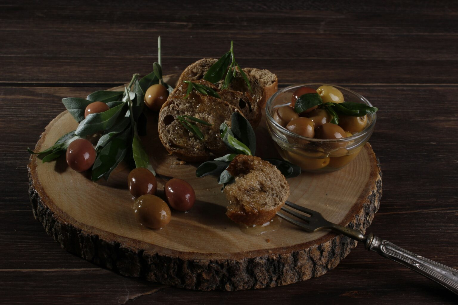 Olives, fresh bread and olive oil arranged on a wooden board